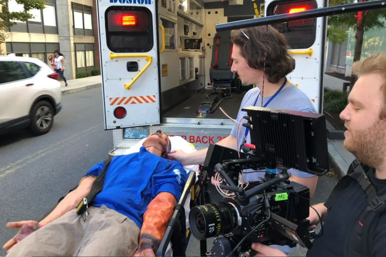 Crew films mannikin burn victim as it is brought into ambulance for medical training video.